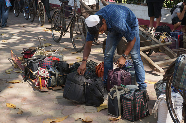 Un dabbawala trie son chargement devant la gare de Churchgate. Crédits : Clément Pairot