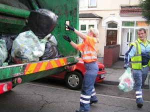 Une femme jetant des ordures dans un camion benne