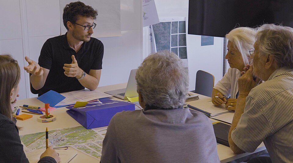 Photographie d’un atelier de design participatif. Les personnes autour de la table sont visiblement de classe sociale moyenne et supérieure avec une majorité de retraités. Crédit : Max Fonseca e Martin Franze / Project PATI / SUPSI, CC BY-SA 4.0, via Wikimedia Commons